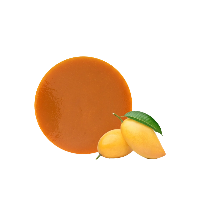 Puree xoài màu cam đậm đặt cạnh hai quả xoài chín vàng còn nguyên cuống lá