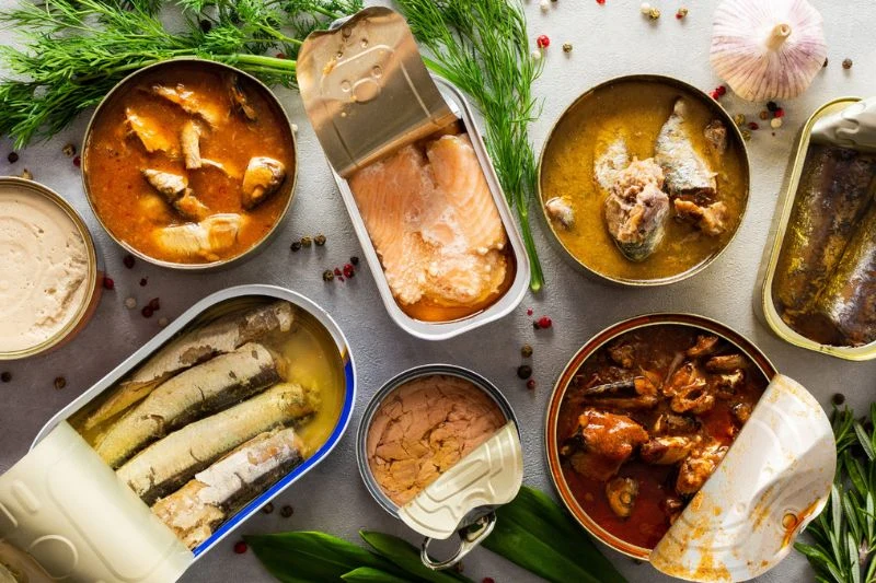 Nhiều hộp cá đóng hộp mở nắp cùng thì là và tỏi, nguyên liệu thực phẩm cho ngành thủy hải sản