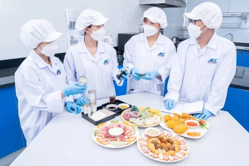 Bốn chuyên viên ACC đeo găng xanh đánh giá cảm quan các đĩa mẫu thịt nguội, chả chiên và salad
