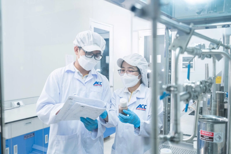 Hai chuyên viên ACC mang găng xanh kiểm tra mẫu bên dây chuyền inox, khâu thử nghiệm nguyên liệu life science